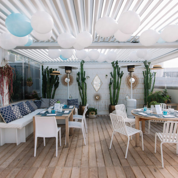 Blue and white decoration on the beach with ballons under the pergola, matching cushions and tableware during MAPIC