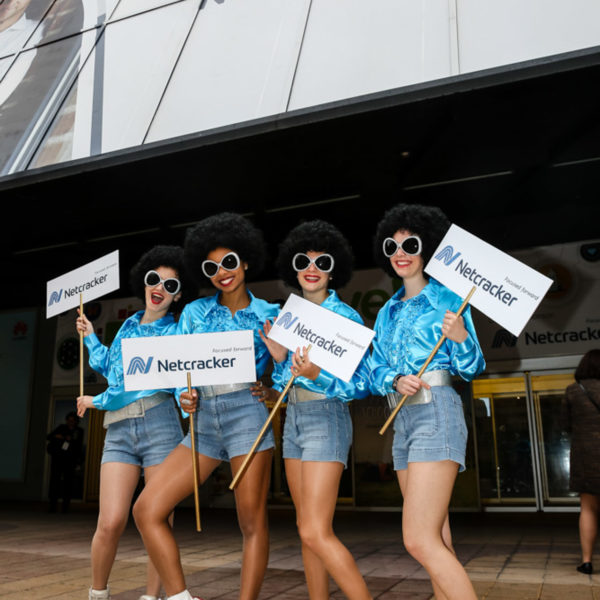 Disco roller girls in front of the congress center drawing attention to the signs they carry to inform guests about the party