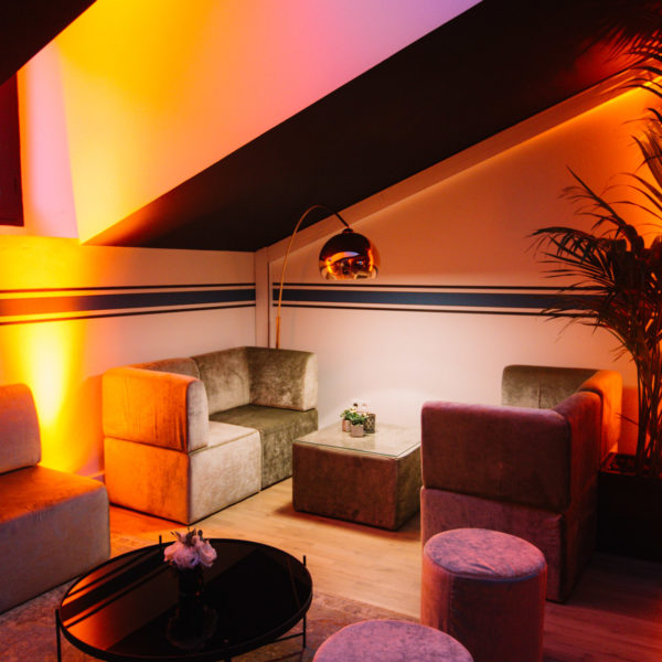 Velvet sofas and chairs with low tables in hushed vibe with orange hot lighting carpet interior design to network during MIPIM