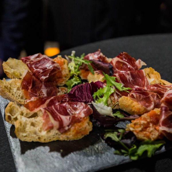 Iberian ham on grilled toast on tray for guests during networking cocktail in venue in the city center