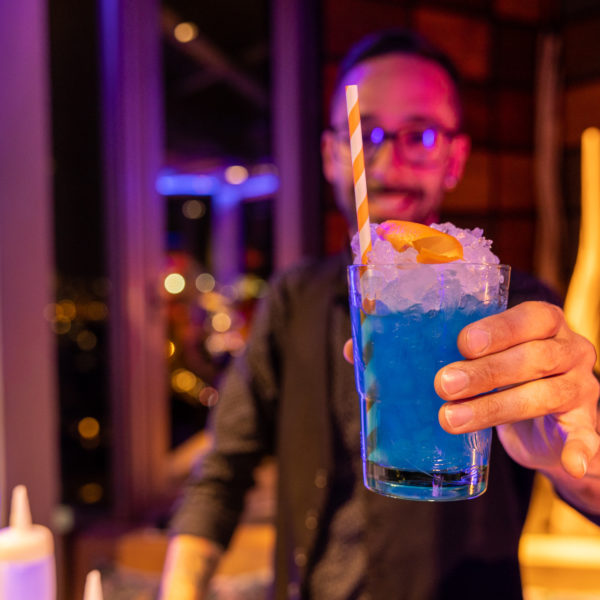 bar tender handing over a corporate blue cocktail during networking event in barcelona for mwc
