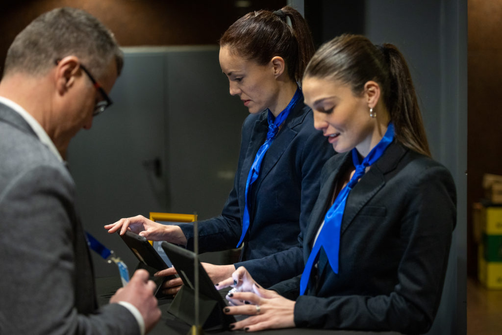 hostesses typing on ipads searching the guests names to filter before guests can enter the venue during networking event in barcelona for MWC