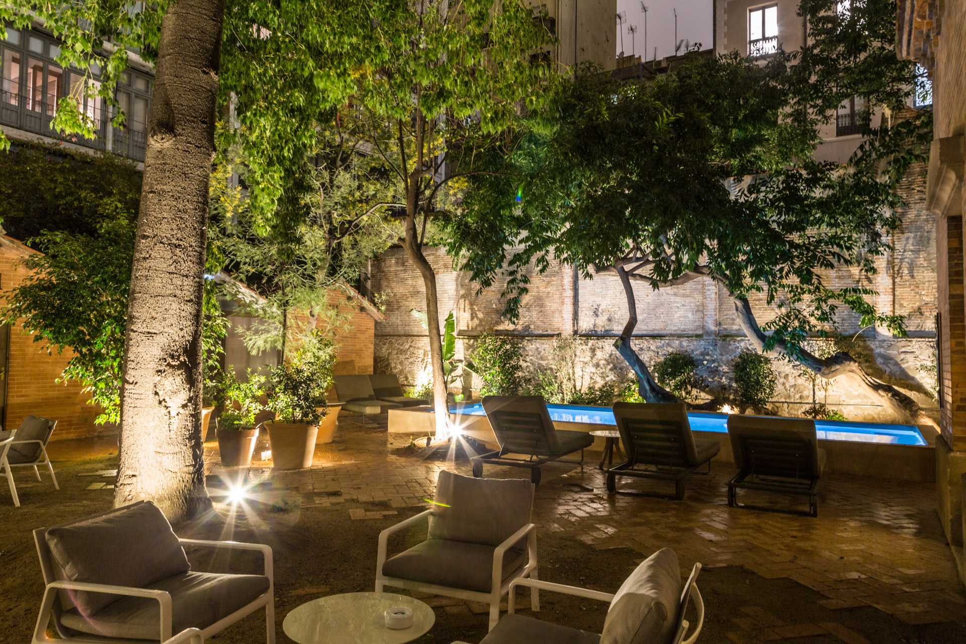 Hidden garden in a secret venue in Barcelona with a lighted swimming pool at night