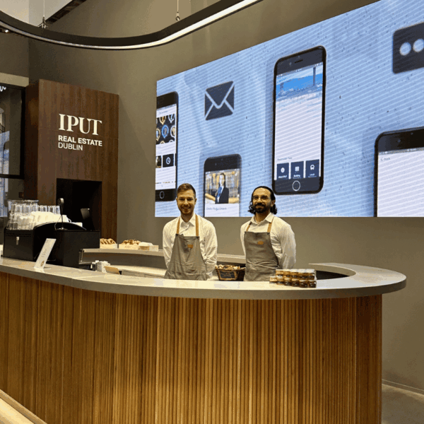 Waiters smiling at the photographer, standing behind the bar at the stand