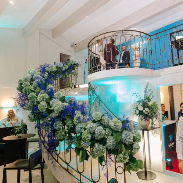 Beautiful flower arrangement along the staircase. Colors are blue, white and green and match the customer logo. There is also a lighting arrangement of cyan enhancing the magical stairs